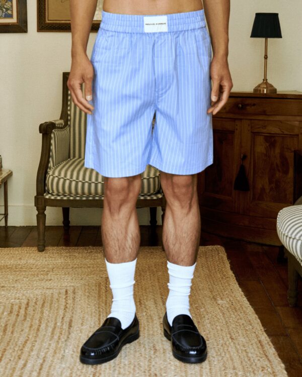 Men's light blue striped unisex casual shorts with white socks and black loafers.