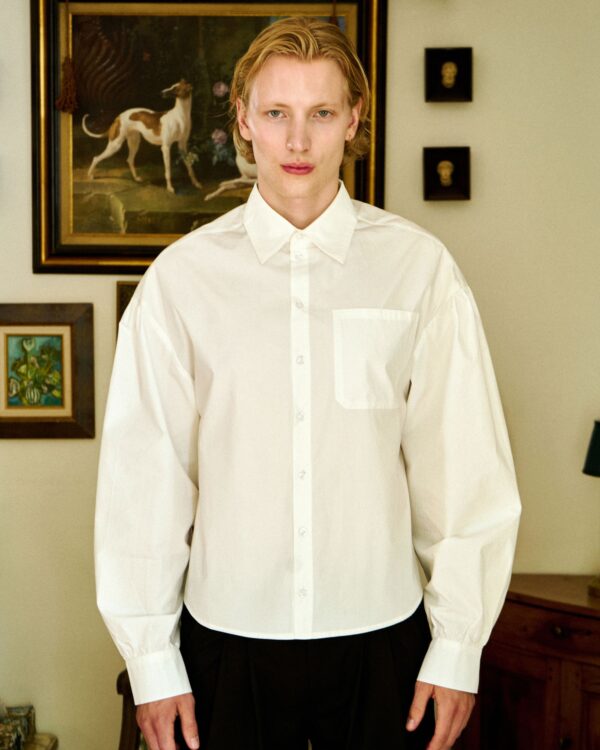 Unisex white button-up shirt with a pocket, modern Parisian style.