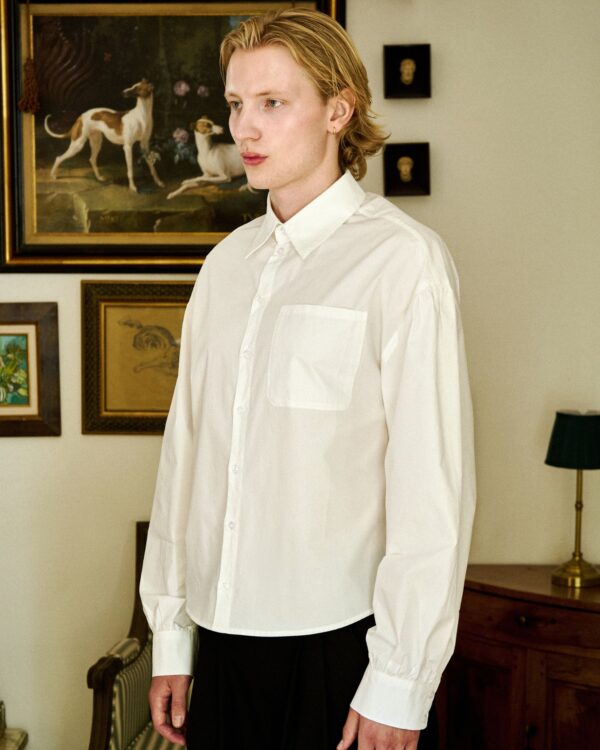 Unisex white button-up shirt from Revivo Avenue in a stylish home setting.