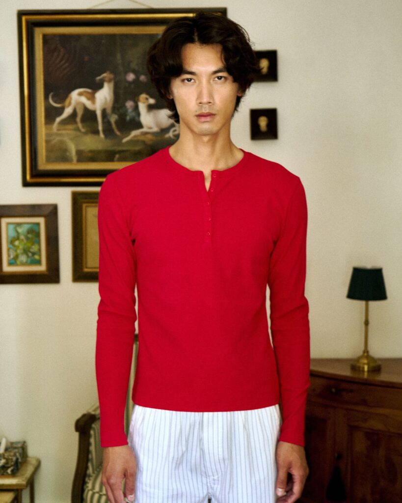 Male model wearing a red unisex top in a stylish indoor setting.