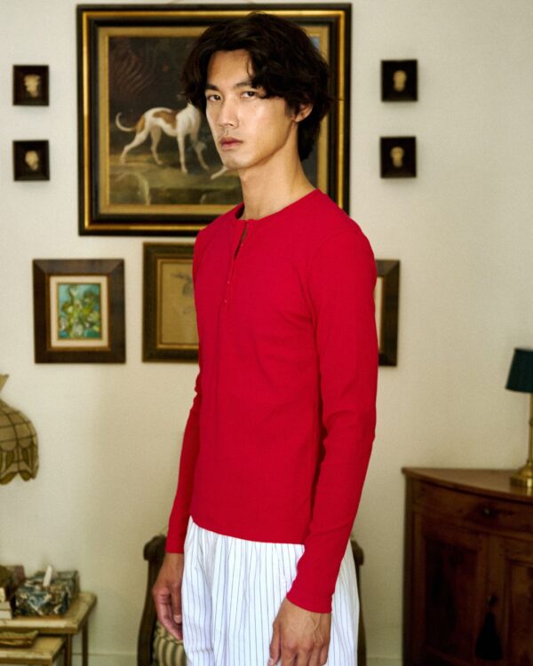 Male model wearing a red unisex sweater in a vintage-style room.