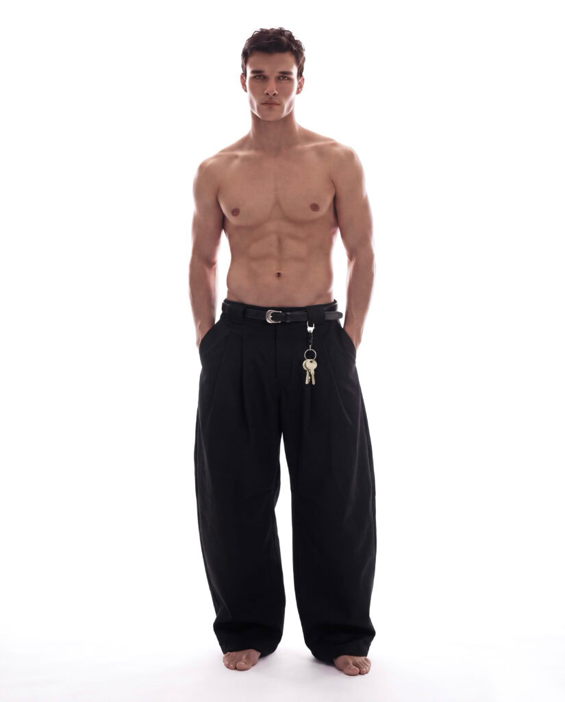 Unisex black wide-leg pants with belt and keychain accessory.