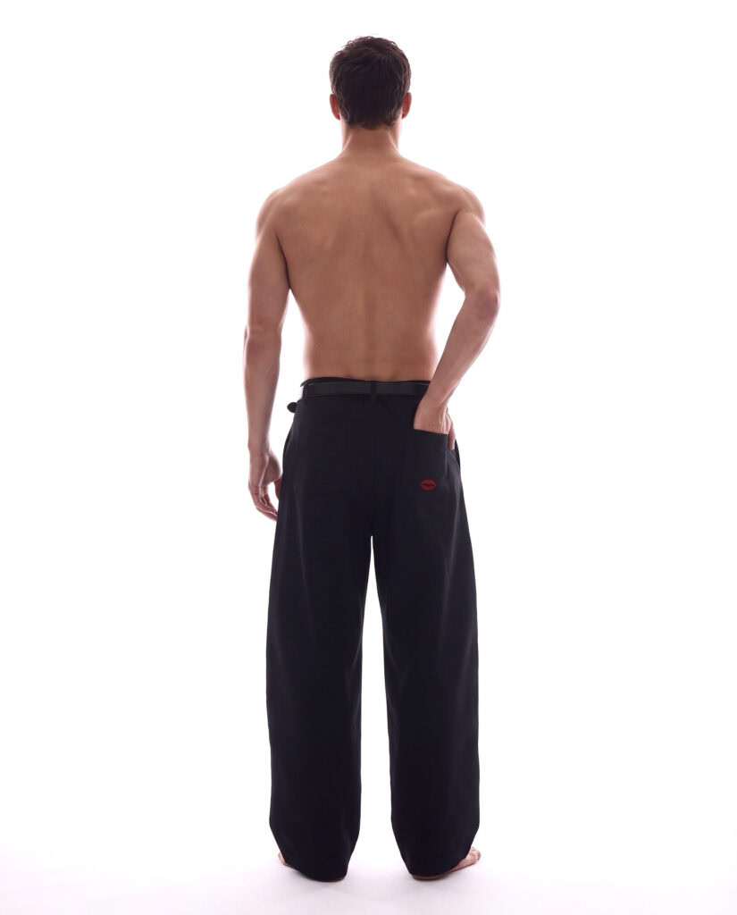 Unisex black wide-leg trousers with red logo, back view, fashion photo.